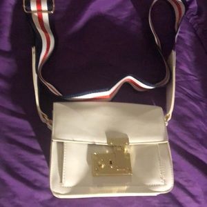 A white bag with a white blue and red stripe strap